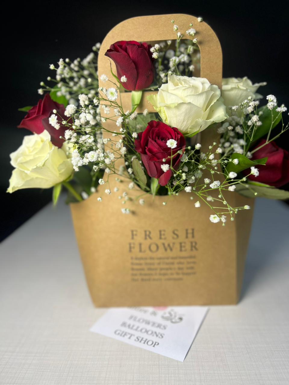 Red and white roses with baby's breath in kraft paper carrier bag